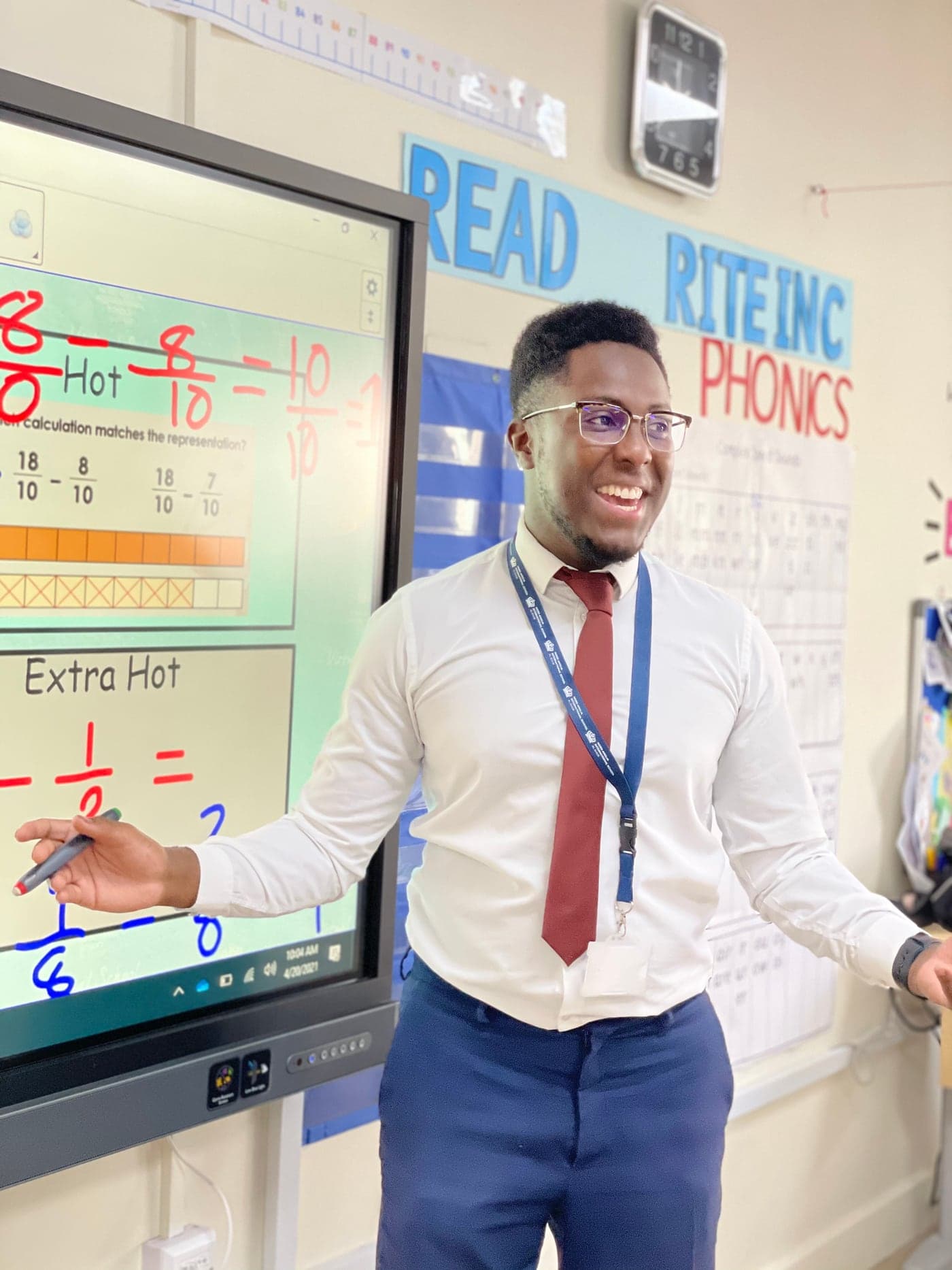 Joe Souassou teaching in a classroom beside an interactive whiteboard